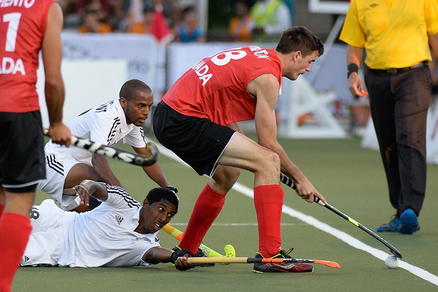 Canada defender Paul Wharton keeps the ball in and away from Trinidad and Tobago midfielders (back) Akim Toussaint and Mickell Pierre during a quarter-final men’s field hockey match at the Pan Am Games in Toronto on Tuesday.  Canada won the match 3-1.