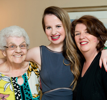 Young teenager stands between her mother and grandmother for a family photo