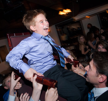 Young man is lifted in the air by family during a Bar Mitzvah celebration