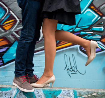 Young trendy couple posing in downtown Toronto in front of a building wall painted with graffiti