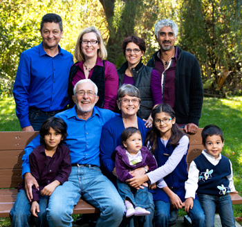 Large family pose with their children and grandchildren on a park bench for a family photograph