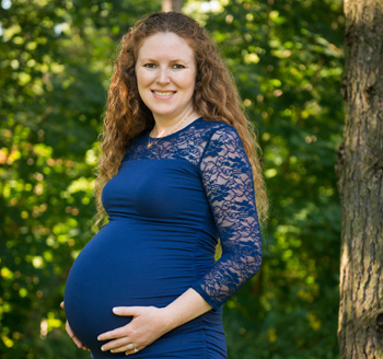 Beautiful young pregnant woman poses in a park for a pregnancy photo