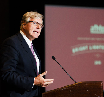 Photograph of a prominent presenter at a conference speaking in front of an audience